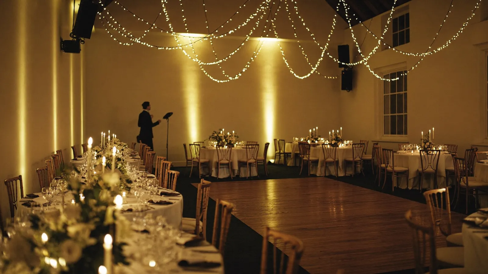 Festlich geschmückter Hochzeitssaal mit Lichterketten, Kerzen und Tanzfläche